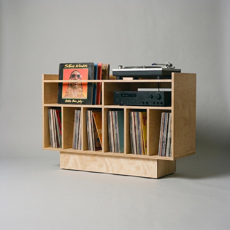 Angled studio view of Groove No.3 record player stand with light birch plywood grain, turntable shelf, receiver space, front album display, and vinyl storage compartments.