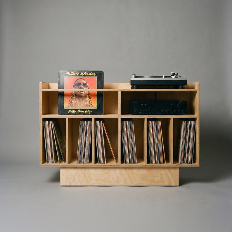 Front view of Groove No.3 birch plywood turntable console with a Stevie Wonder record on display, audio equipment shelf, and six vertical vinyl storage compartments.