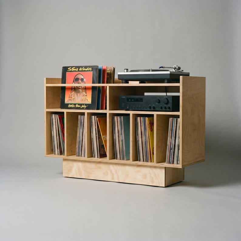 Angled studio view of Groove No.3 record player stand with light birch plywood grain, turntable shelf, receiver space, front album display, and vinyl storage compartments.