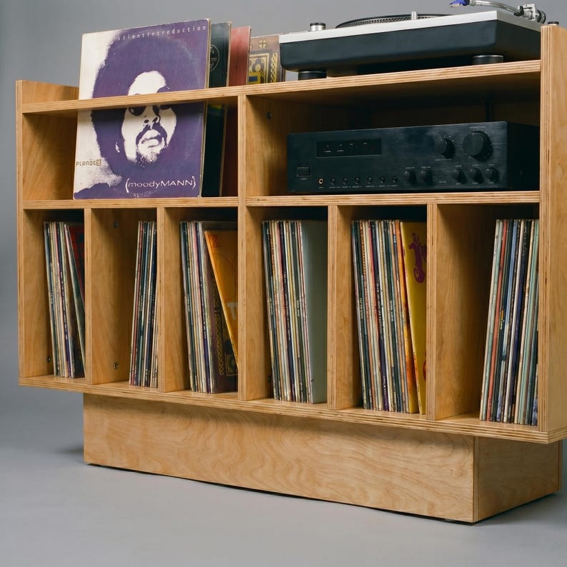Close-up of Groove No.3 vinyl storage console showing layered birch plywood edges, open amplifier shelf, turntable platform, and organized record compartments.