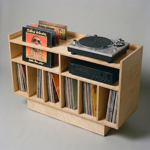 Top angled view of Groove No.3 birch plywood record player stand with turntable, amplifier shelf, front-facing album display, and six vinyl storage compartments.