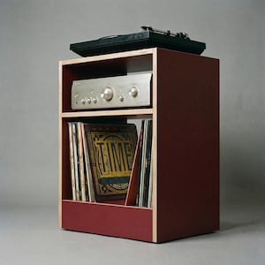 Modular plywood record player stand in oxide red with natural plywood edges shown from a front angled view against a gray background. A black turntable sits on top with a silver stereo component below and vinyl records stored upright in the lower section.
