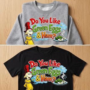 Op de afbeelding: Een grijze sweatshirt en een zwart t-shirt met de tekst "Do You Like Green Eggs & Ham?" in rood, groen en blauw. Het ontwerp bevat een stripfiguur en een bord met groene eieren en ham.
