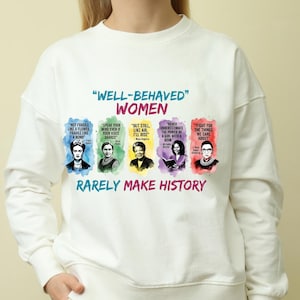May include: A white sweatshirt with the slogan "WELL-BEHAVED WOMEN RARELY MAKE HISTORY." The design includes portraits of influential women and their quotes, in a range of colours. The text is in blue, green, yellow, purple, and red.