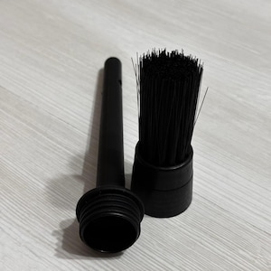 Puede incluir: Un accesorio de aspiradora negro que incluye una boquilla larga y delgada con base roscada y un cabezal de cepillo cil&iacute;ndrico separado con cerdas negras r&iacute;gidas. Ambos componentes est&aacute;n hechos de pl&aacute;stico negro mate para la limpieza.