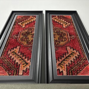 Pode incluir: Duas pe&ccedil;as de arte de parede emolduradas com um design de tapete vermelho e dourado. Os tapetes t&ecirc;m um medalh&atilde;o central e bordas geom&eacute;tricas. As molduras retangulares pretas criam um contraste com as cores do tapete.