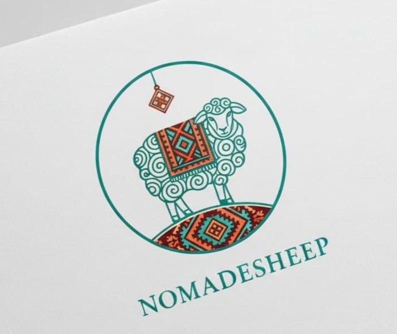 Puede incluir: Un logotipo circular que muestra una oveja estilizada con lana rizada, que lleva una manta estampada con dise&ntilde;os geom&eacute;tricos en naranja, azul cerceta y rojo oscuro. Un peque&ntilde;o dije cuadrado cuelga arriba. El texto NOMADESHEEP aparece en azul cerceta.