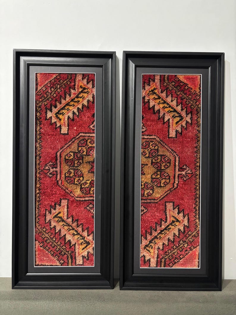 Pode incluir: Duas obras de arte de parede retangulares emolduradas. Cada uma apresenta uma se&ccedil;&atilde;o de um tapete padronizado em vermelho, dourado e preto. As molduras s&atilde;o pretas com um passe-partout branco. O design do tapete inclui formas geom&eacute;tricas e detalhes intrincados.