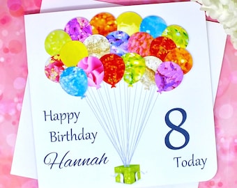 Può includere: Un biglietto bianco con un design di palloncini colorati. Il biglietto dice "Buon compleanno Hannah 8 Oggi".