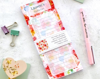 Può includere: Un blocco note per liste di cose da fare con motivi floreali con il testo "Lauren's To-Do List". Il blocco note presenta un design ad acquerello con fiori rossi, rosa e gialli. È visibile anche una penna rosa con la scritta "you're better than unicorns".
