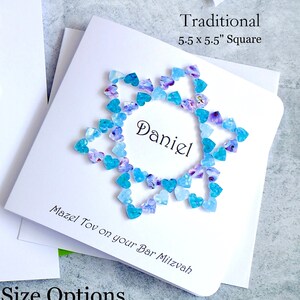 May include: A white card with a blue and purple heart design surrounding the name "Daniel". The card reads "Traditional 5.5 x 5.5" Square" and "Mazel Tov on your Bar Mitzvah".