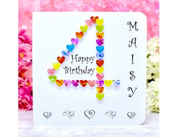 Può includere: Un biglietto d'auguri quadrato bianco con un grande numero 4 composto da piccoli cuori colorati e decorati. Il testo Happy Birthday è stampato in nero, con il nome MAISY allineato verticalmente sul lato destro del biglietto.