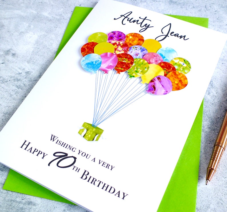 May include: A white card with a colorful balloon design and the text "Wishing you a very Happy 70th Birthday" and "Aunty Jean".