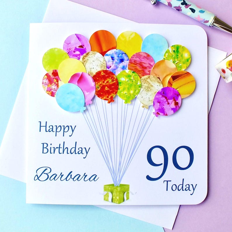 May include: A white card with a blue and white balloon design. The card says "Happy Birthday Barbara 90 Today".
