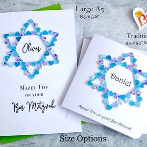 May include: Two white cards with blue and purple heart-shaped embellishments forming a Star of David. The cards are personalized with the names "Oliver" and "Daniel" and the text "Mazel Tov on your Bar Mitzvah". The cards are available in two sizes: 8.3 x 5.8 inches and 5.5 x 5.5 inches.