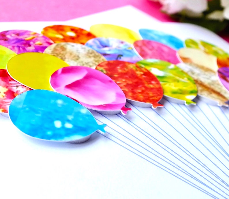 May include: A cluster of colorful balloons with various patterns, including floral, abstract, and geometric designs. The balloons are tied together with strings and are arranged in a semi-circle.