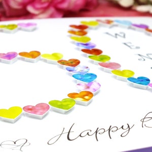May include: A white card with the number 30 made out of colorful hearts. The card says "Happy Birthday" in cursive writing.
