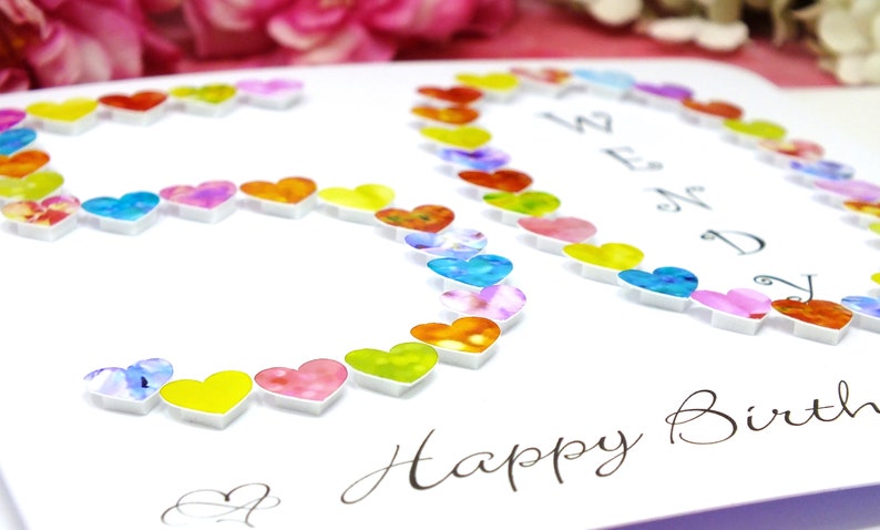 May include: A white card with the number 30 made out of colorful hearts. The card says "Happy Birthday" in cursive writing.