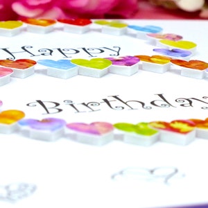 May include: A white card with the words "Happy Birthday" written in black cursive. The number eight is formed with a circle of colorful hearts.
