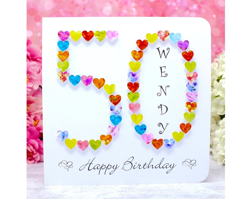 May include: A white card with a colorful heart design forming the number 50. The word "WENDY" is spelled out vertically in the center of the card. The card reads "Happy Birthday" at the bottom.