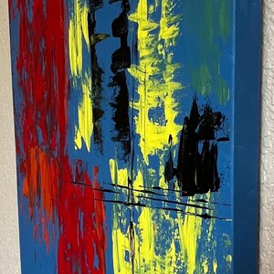 May include: A rectangular canvas painting featuring an abstract composition with a vibrant blue background. The artwork displays bold, vertical brushstrokes in bright yellow, deep red, and black, accented by thin, horizontal black lines.