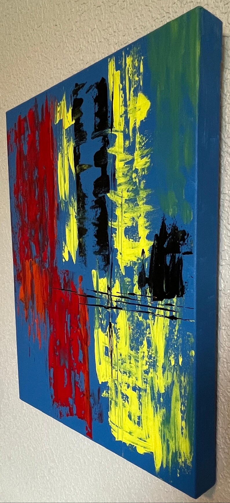 May include: A rectangular canvas painting featuring an abstract composition with a vibrant blue background. The artwork displays bold, vertical brushstrokes in bright yellow, deep red, and black, accented by thin, horizontal black lines.
