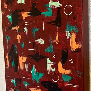 May include: An abstract painting on a deep maroon background featuring scattered brushstrokes in teal, black, orange, and light green. The composition includes two thin white circular outlines and several horizontal white lines painted across the canvas.