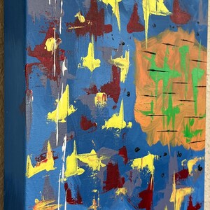 Pu&ograve; includere: Un dipinto astratto su tela rettangolare con uno sfondo blu intenso. La composizione include forme gialle simili a stelle sparse, macchie rosso scuro e una grande forma circolare arancione sul lato destro con tratti orizzontali verdi.