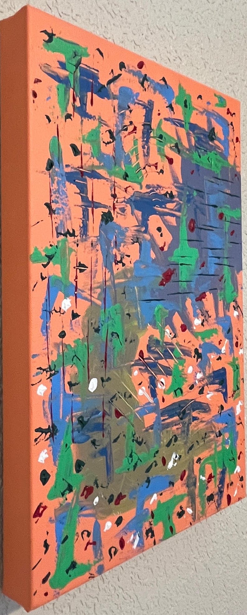 May include: A rectangular canvas painting featuring an orange background layered with abstract brushstrokes in blue, green, black, and white. The composition includes vertical and horizontal paint marks, splatters, and drips across the surface.