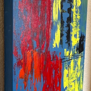 May include: An abstract painting on a rectangular canvas featuring a blue background with thick, textured brushstrokes in vibrant red, bright yellow, and black. The paint application creates a layered effect with vertical streaks and bold color blocks.