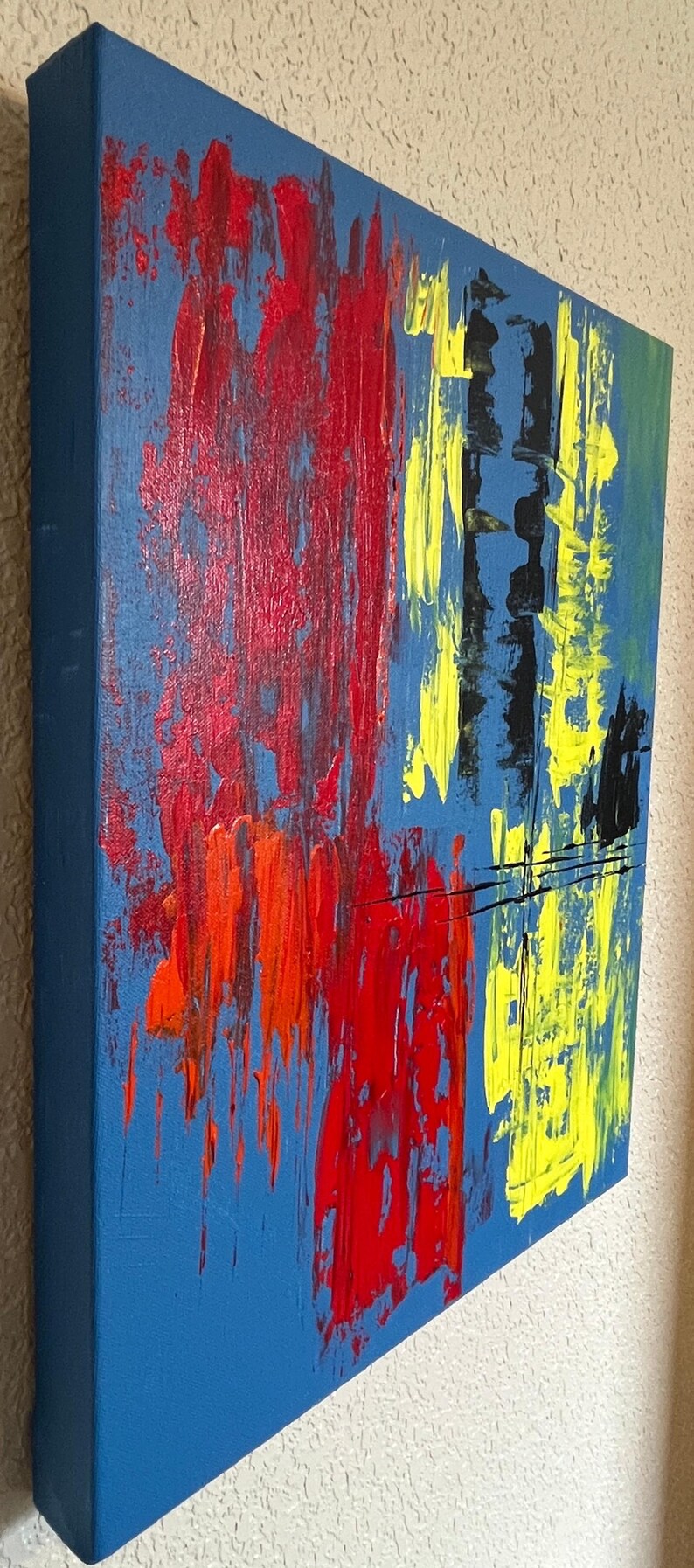 May include: An abstract painting on a rectangular canvas featuring a blue background with thick, textured brushstrokes in vibrant red, bright yellow, and black. The paint application creates a layered effect with vertical streaks and bold color blocks.