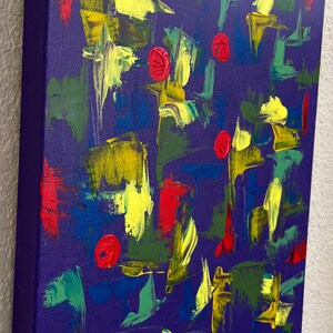 May include: A square canvas painting featuring a deep purple background with abstract brushstrokes in bright yellow, forest green, and vibrant red. The composition includes several small, circular red textured elements scattered across the surface.