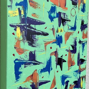 May include: A rectangular canvas painting featuring a light mint green background with abstract brushstrokes in shades of dark blue, orange, yellow, and purple. The composition includes scattered paint dabs and thin lines across the surface.