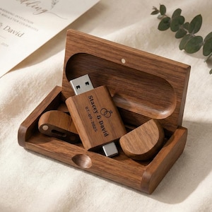 May include: A wooden USB flash drive and matching wooden case. The USB drive is engraved with the names "Stacey & David" and the date "07-09-2023", along with wedding rings. The case is open, revealing the drive and a small wooden piece.