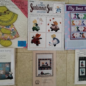 May include: A collection of quilting pattern books featuring designs with children, sunbonnet characters, and quilt block patterns. The books have titles like "Children's Designs," "Sunbonnet Sue," and "My Best Friend." The color palette includes pastels and primary colors.