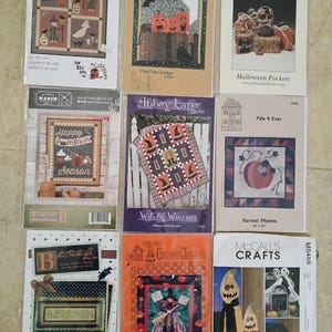 May include: A collection of Halloween-themed quilt and craft patterns. The patterns feature images of witches, pumpkins, ghosts, and other spooky elements. The patterns are in various sizes and styles, perfect for creating seasonal decorations.