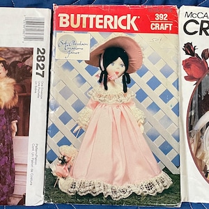 May include: Three vintage craft pattern envelopes featuring doll designs. The patterns are from McCall's and Butterick, showcasing dolls in various outfits, including dresses and coats. The envelopes display illustrations of the finished dolls.