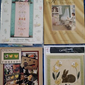 May include: Four craft pattern books. Titles include "Spring Has Sprung", "A Blessing From Above", "Springtime Threads", and "Carried Away Designs in Wool". The books feature cross-stitch and needlepoint designs with spring and Easter themes.
