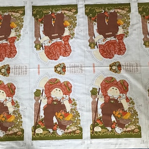 May include: A white fabric with a repeated pattern of a red-haired girl holding a basket of vegetables. The girl is wearing brown overalls and a white shirt. The fabric is meant to be used for making a doll.