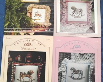 Op de afbeelding: Vier kruissteekpatroonfolders met carrousel- en schommelpaardontwerpen. De folders heten "Carousel Fantasy", "Misty", "Chestnut" en "Trotter". Elke folder toont een gedetailleerde afbeelding van het voltooide kruissteekproject.