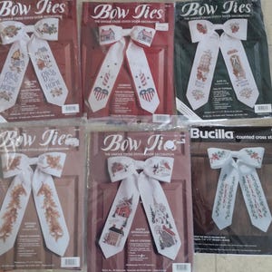 May include: A set of ten counted cross stitch patterns for door bows. The patterns feature various themes, including holiday, home, and Americana. Each pattern includes instructions and a color chart.