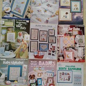 May include: A collection of cross-stitch pattern leaflets featuring baby-themed designs. The leaflets showcase various projects, including bibs, samplers, and alphabet charts. The color palette includes soft pastels and the designs feature baby animals and nursery motifs.
