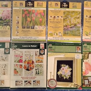 May include: Eight rectangular Learn to Paint instructional kits featuring various floral and landscape designs. Each package displays step-by-step painting techniques, finished project examples, and branding by Donna Dewberry on a tan or white background.