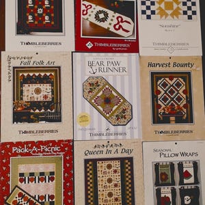 May include: A collection of nine Thimbleberries quilting pattern booklets featuring various designs including Winterfest Wall Quilt, Big Bow table runner, Thimbleberries Village, Fall Folk Art, Bear Paw Runner, Harvest Bounty, Pack-A-Picnic, Queen In A Day, and Seasonal Pillow Wraps.