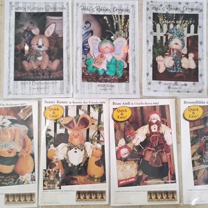 May include: A collection of seven craft pattern packets featuring handmade bunny and doll designs. The packets showcase various characters, including bunnies, a bear, and a doll, with titles like "Butterscotch" and "Bumble Bunny." Each packet has a unique design.