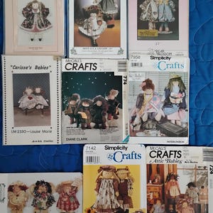 May include: A collection of eight vintage doll-making patterns. The patterns feature various styles of dolls, including a doll with a red dress and a doll with a blue dress. The patterns are printed on paper and have a variety of colors and designs.