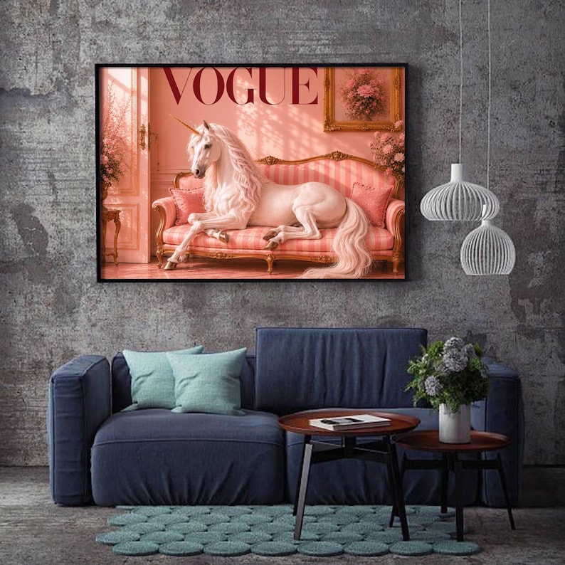 May include: A framed print featuring a white unicorn reclining on a pink striped sofa, with the word "VOGUE" in large letters. The artwork is set in a pink-toned room, with a blue sofa and decor in the foreground.