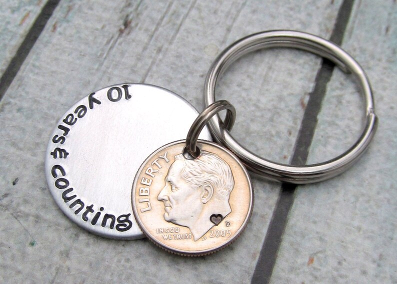 May include: A silver keychain with a round tag that says "counting years 10" and a 2005 dime with a heart on it.