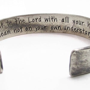 Puede incluir: Pulsera de plata con acabado desgastado y una inscripci&oacute;n grabada: "Trust in the Lord with all your heart lean not on your own understanding."