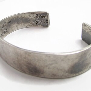 Puede incluir: Pulsera de plata con una inscripci&oacute;n que dice "heart + minding" en un lado y "Prov. 3:4-5" en el otro.
